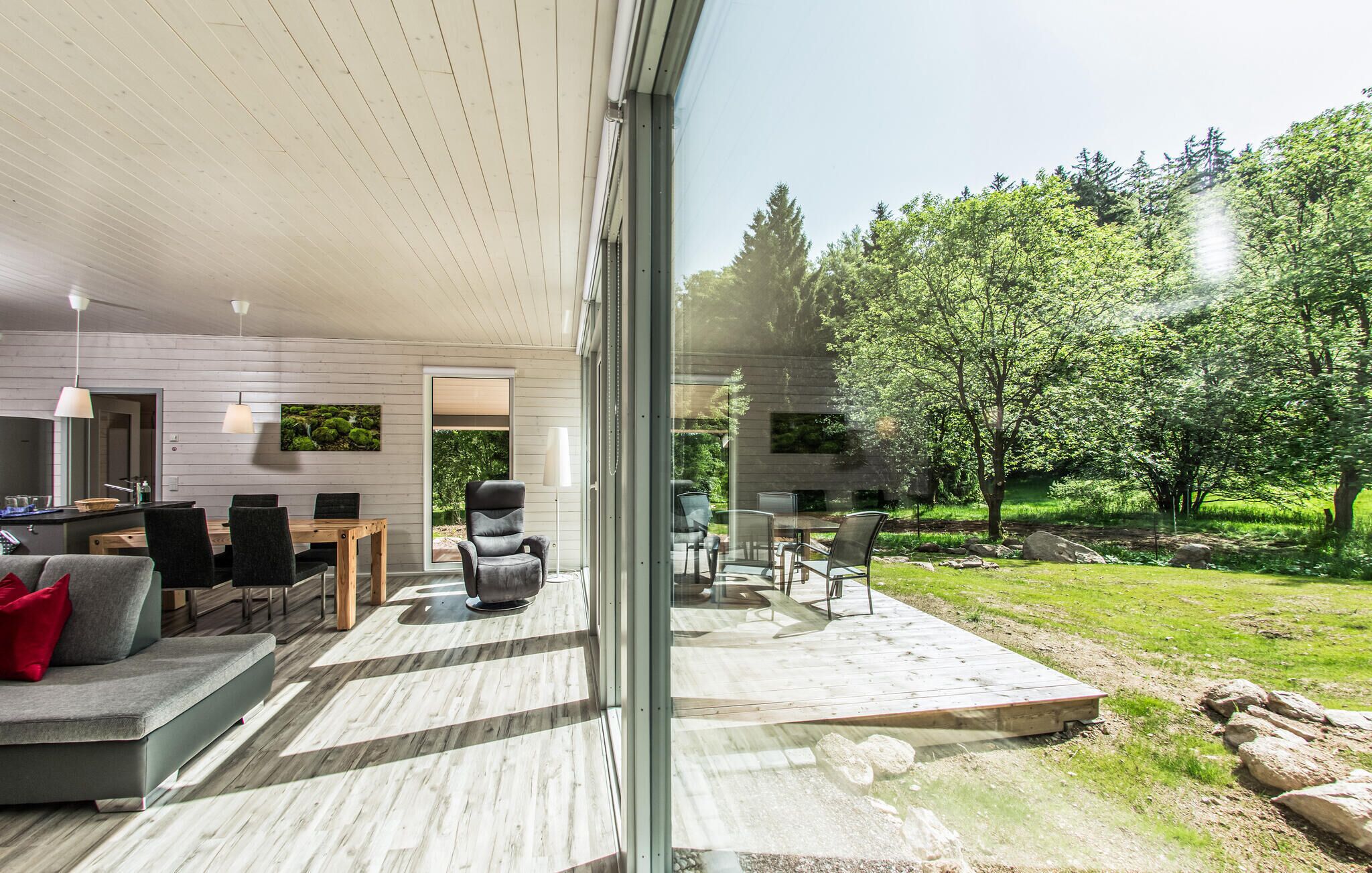 Una casa moderna con un amplio salón, un comedor y un gran ventanal que da a un jardín.