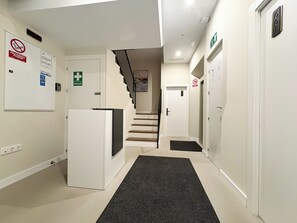 A clean, modern hallway with a reception desk, a staircase, and emergency exit signs.