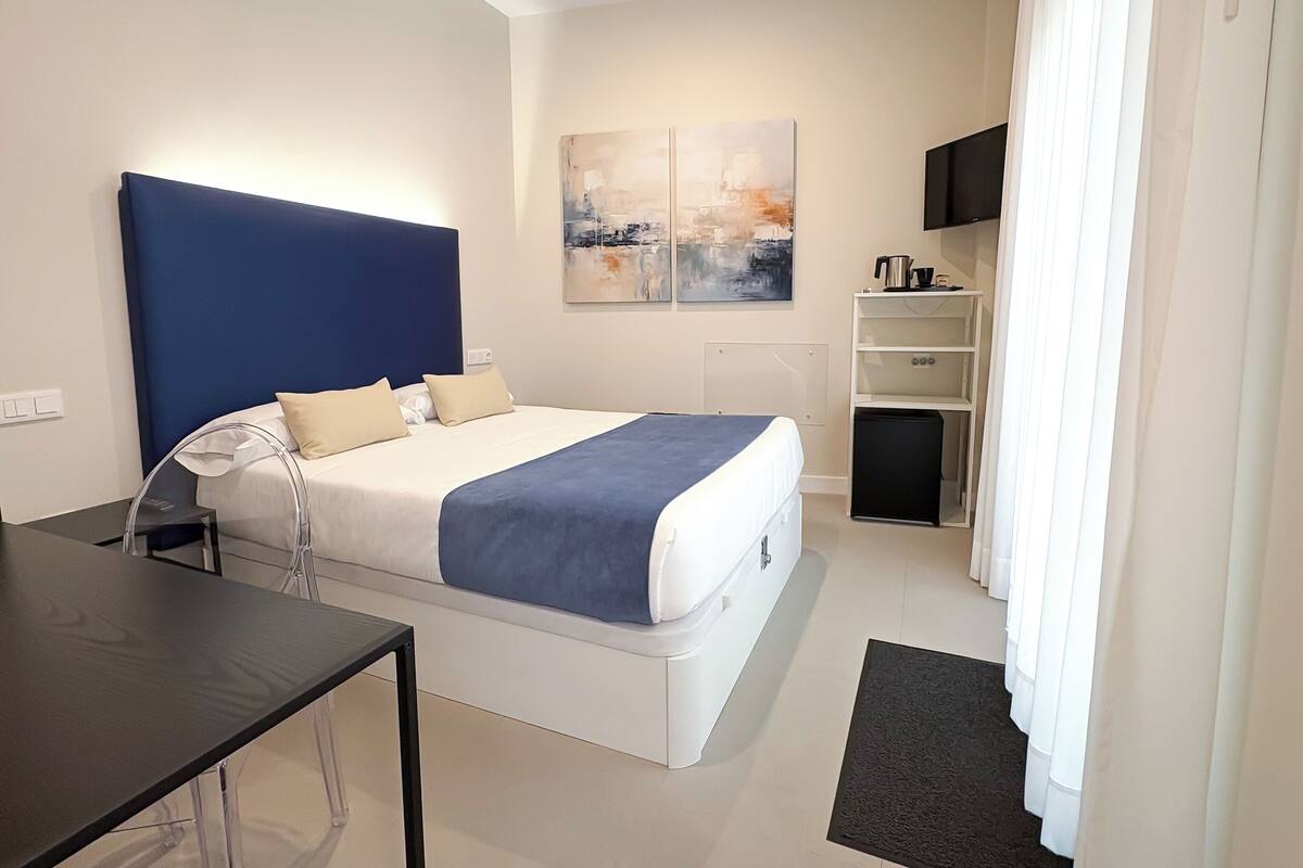 Quarto de hotel moderno com uma cama grande, uma escrivaninha, televisão de tela plana e máquina de café.