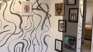 A hallway with a modern abstract wall art, a framed photograph, and several framed pictures on the wall. - Cozy apartment near to the center. (Guatavita)