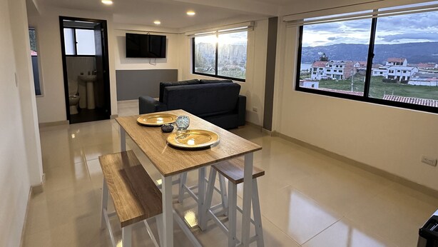 A modern kitchen with a dining table, a sofa, and a large window offering a city view. - Cozy apartment near to the center. (Guatavita)