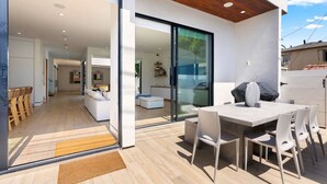 A modern house with a spacious patio, a dining area, and a living room with a sofa and a coffee table. - Pool, spa, rooftop, back yard, gym, fire pit, games and more (Los Angeles)