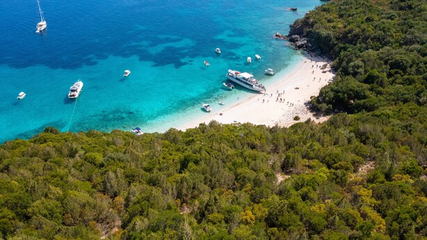 Une vue aérienne d’une zone côtière avec des bateaux, une plage et une végétation luxuriante.