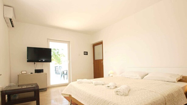 Ein Schlafzimmer mit Bett, Fernseher, Schreibtisch und Stuhl.