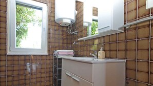 Ein Badezimmer mit Fenster, Waschbecken, Spiegel und Handtuchhalter.