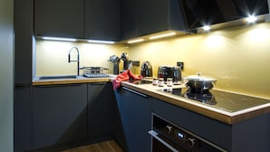 A modern kitchen with dark cabinetry, a wooden countertop, a sink, a stove, and a microwave.