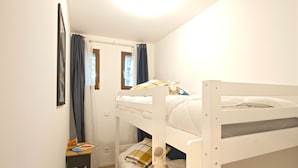 A bunk bed room with a small table and a window with curtains.