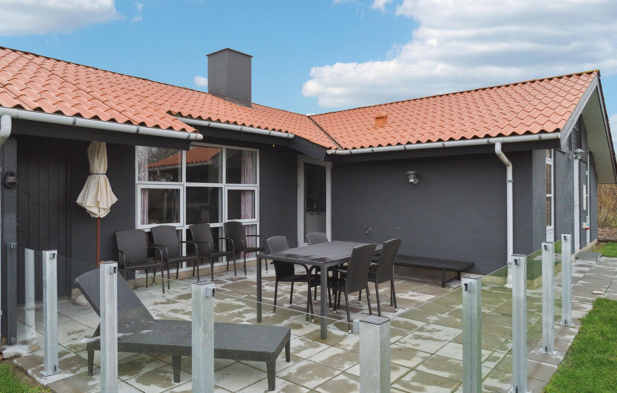 A patio with a table and chairs, a covered seating area, and a building with a tiled roof.