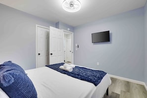 A bedroom with a bed, a TV mounted on the wall, and a door. - Cozy Hot Tub 4BR Poconos Home Near All Attractions (Tobyhanna)