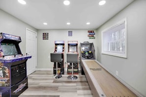 A hallway with arcade games, a wooden bench, and a window with blinds. - Cozy Hot Tub 4BR Poconos Home Near All Attractions (Tobyhanna)