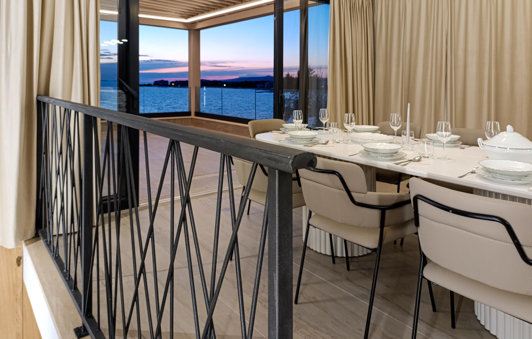Comedor con mesa dispuesta para seis personas, con vista a un cuerpo de agua.