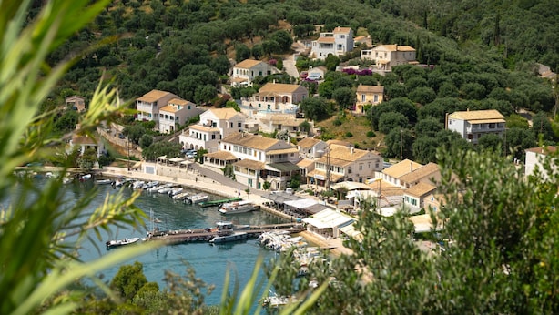 A coastal village with houses along a waterfront, boats docked at the pier, and lush greenery in the background. - Spiros in Saint Stephanos, Corfu - Idyllic Mediterranean Retreat (Saint Stephanos N/E)