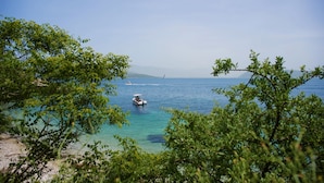 A coastal scene with a boat on the water, surrounded by greenery and clear skies. - Spiros in Saint Stephanos, Corfu - Idyllic Mediterranean Retreat (Saint Stephanos N/E)