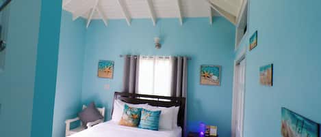 A bedroom with a bed, a nightstand, a ceiling fan, and wall art.