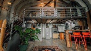 Un loft espacioso con techo alto, vigas a la vista y un nivel entre piso.