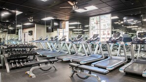 Un gimnasio con cintas de correr, mancuernas y máquinas de pesas.