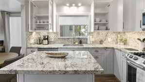 A modern kitchen with white cabinetry, a granite countertop, and a built-in stove.