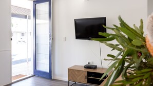 A room with a television mounted on the wall, a wooden cabinet, and a door leading to an outdoor area. - Motel on Becker (Tintinara)