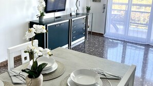 A modern kitchen with a TV, cabinets, and a dining area with a table set for two.
