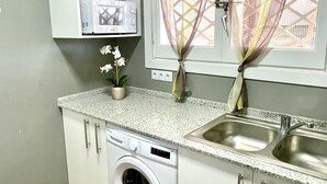 A compact kitchen with a washing machine, a microwave, and a sink.