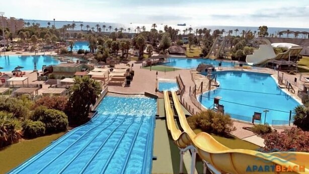 A resort with multiple swimming pools, water slides, and a view of the ocean.