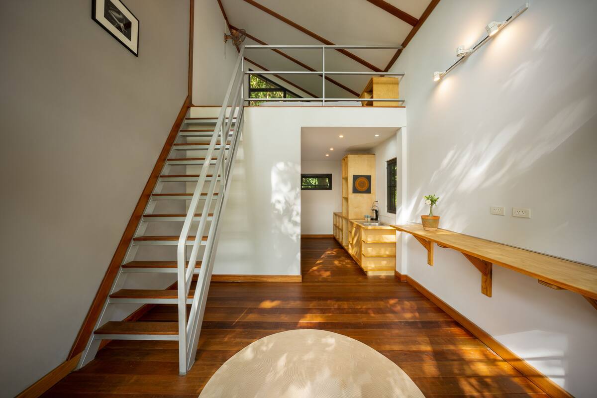 Ein modernes Interieur mit einer Holztreppe, einer Zwischenebene und einer Küchenzeile.