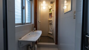 Un baño con lavamanos blanco, un espejo y una ducha.