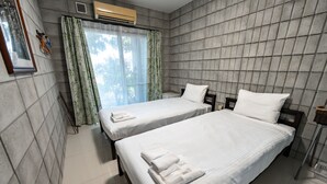Habitación de hotel con dos camas, una ventana con cortinas, un aire acondicionado y un cuadro colgado en la pared.