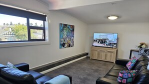 A modern living room with a large window, a flat-screen TV, and a wooden cabinet.