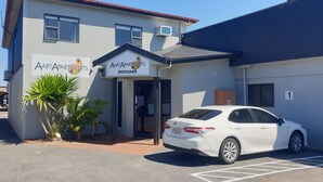 A building with a sign reading "AARTAPARTMENTS ENTRANCE" and a white car parked in front.