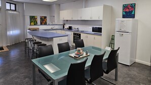 Une cuisine moderne avec des armoires blanches, un îlot de couleur bleue et un réfrigérateur.