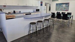 Une cuisine moderne avec des meubles blancs, un plan de travail bleu et un îlot central doté de tabourets.