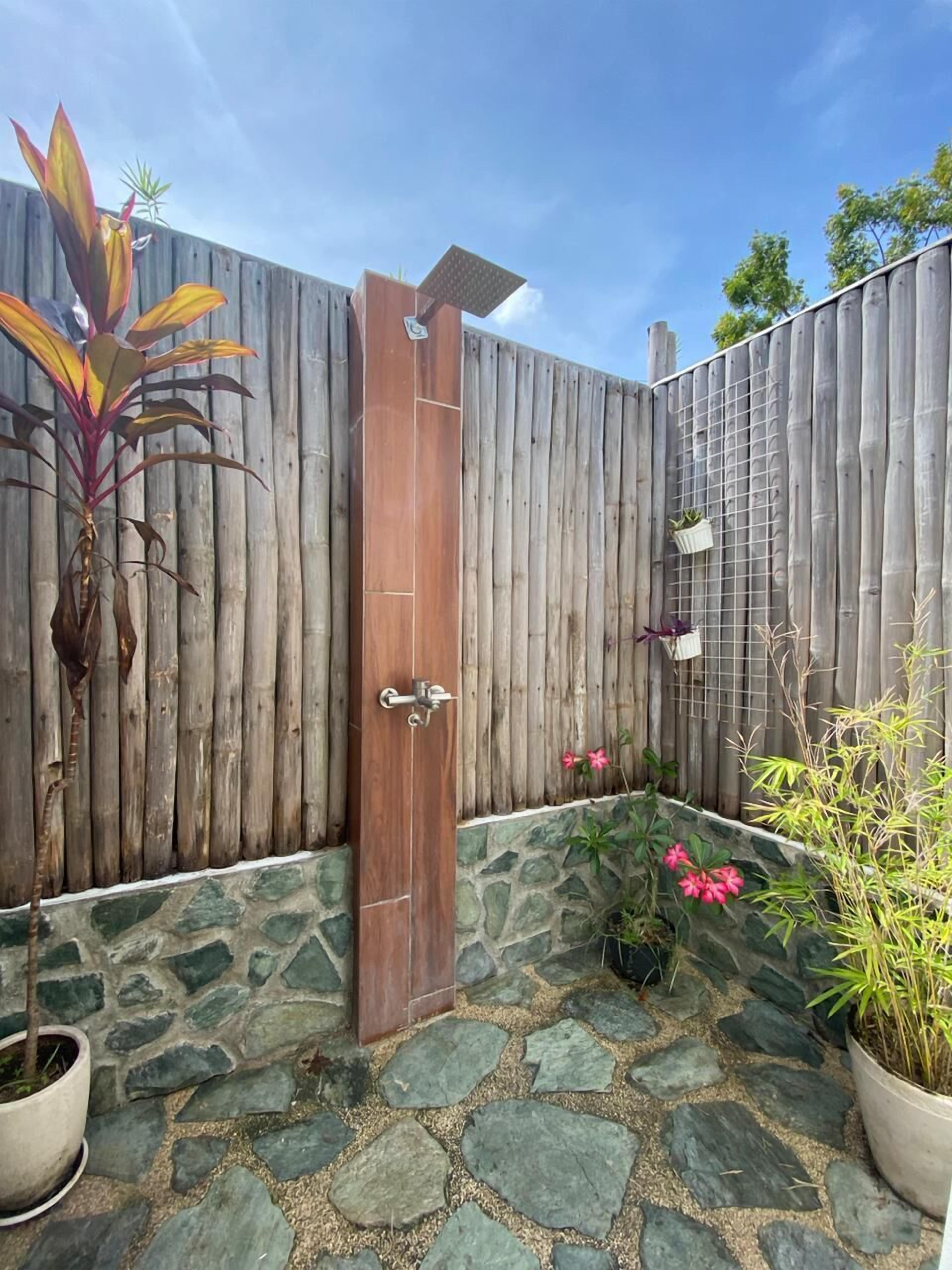 Una puerta de madera con manija de metal, un camino de piedra y plantas en macetas.