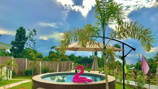 A hot tub with a pink flamingo float, surrounded by a wooden deck and palm trees. - Kalipay Bungalows (Alcoy)