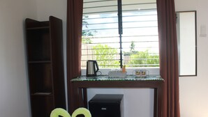 A hotel room with a bed, a small desk with a kettle, a basket, and a framed picture on the wall. - Kalipay Bungalows (Alcoy)