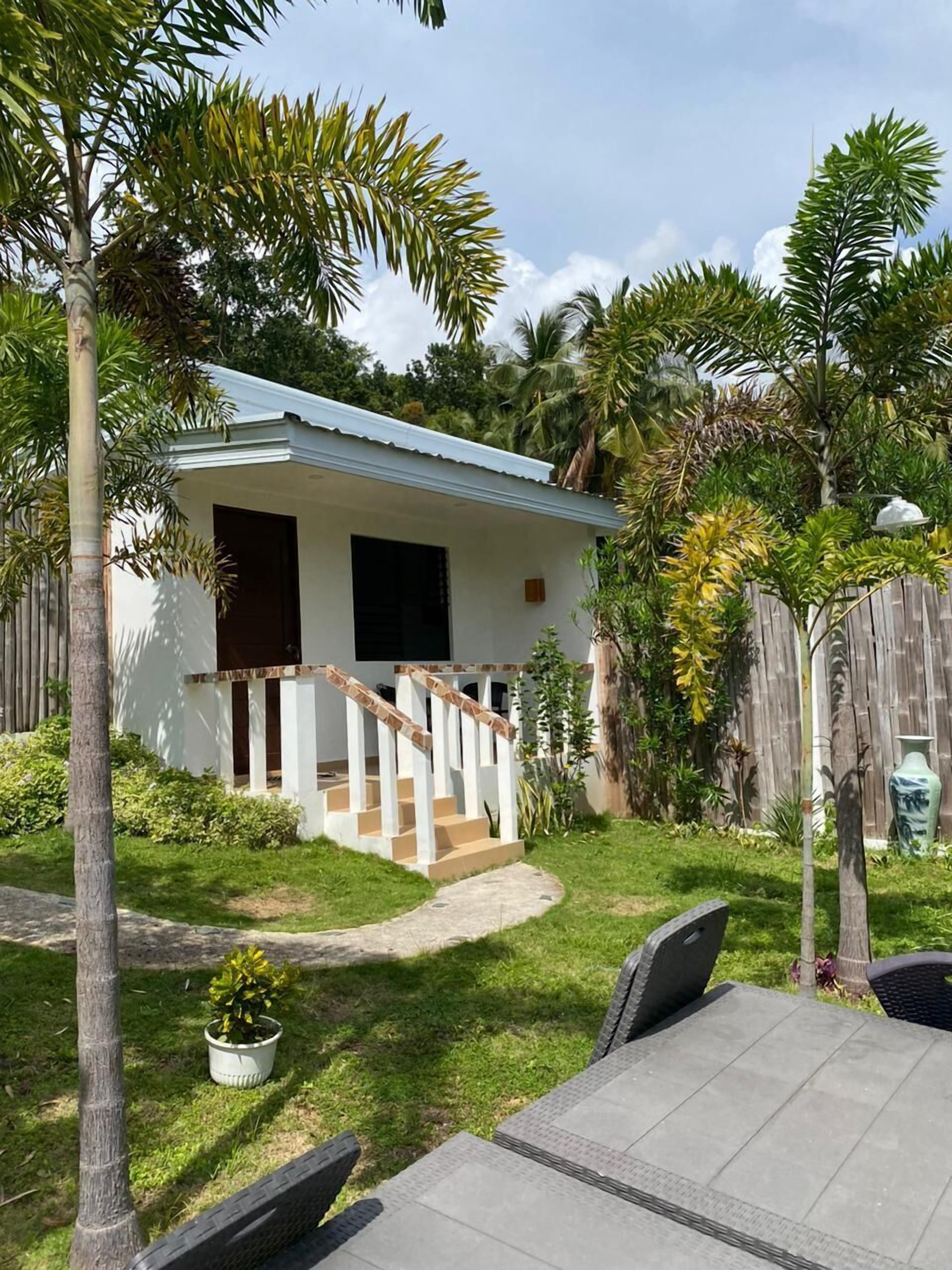 A house with a white exterior, a wooden deck, and a small porch with a staircase.