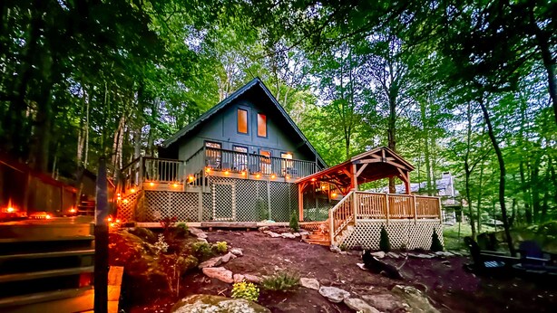 A cabin with a porch and a deck, surrounded by trees and a stone pathway. - 4 min Beech Mtn. Gem: Cabin Retreat near Slopes & Trails 
Pet friendly (Beech Mountain)