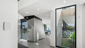 A modern interior with a glass door leading to a balcony, a staircase, and a visible outdoor area with plants. - KARAT Villa Serendibida (Playa Paraiso)