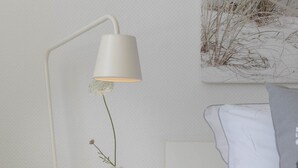 Ein weißer Nachttisch mit einer Lampe, einer kleinen Schale und einem grünen Apfel.