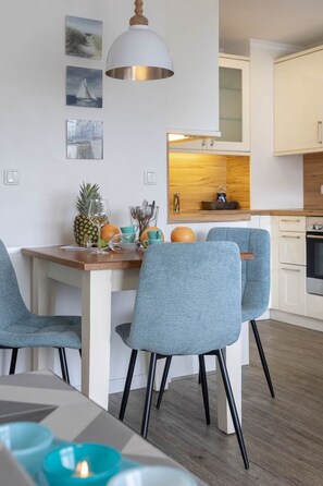 Une cuisine moderne avec des armoires blanches, un plan de travail en bois et un luminaire suspendu.