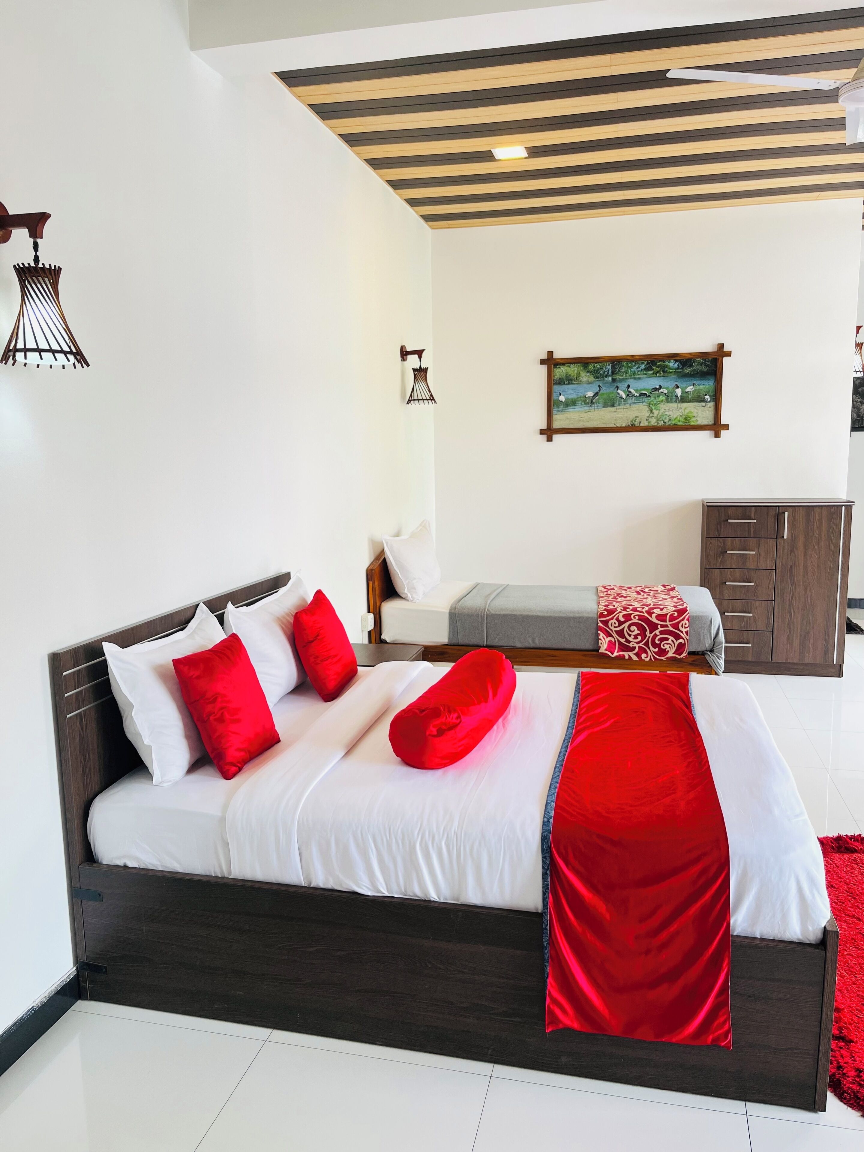 A modern bedroom with a wooden bed frame, white bedding, and red accents.