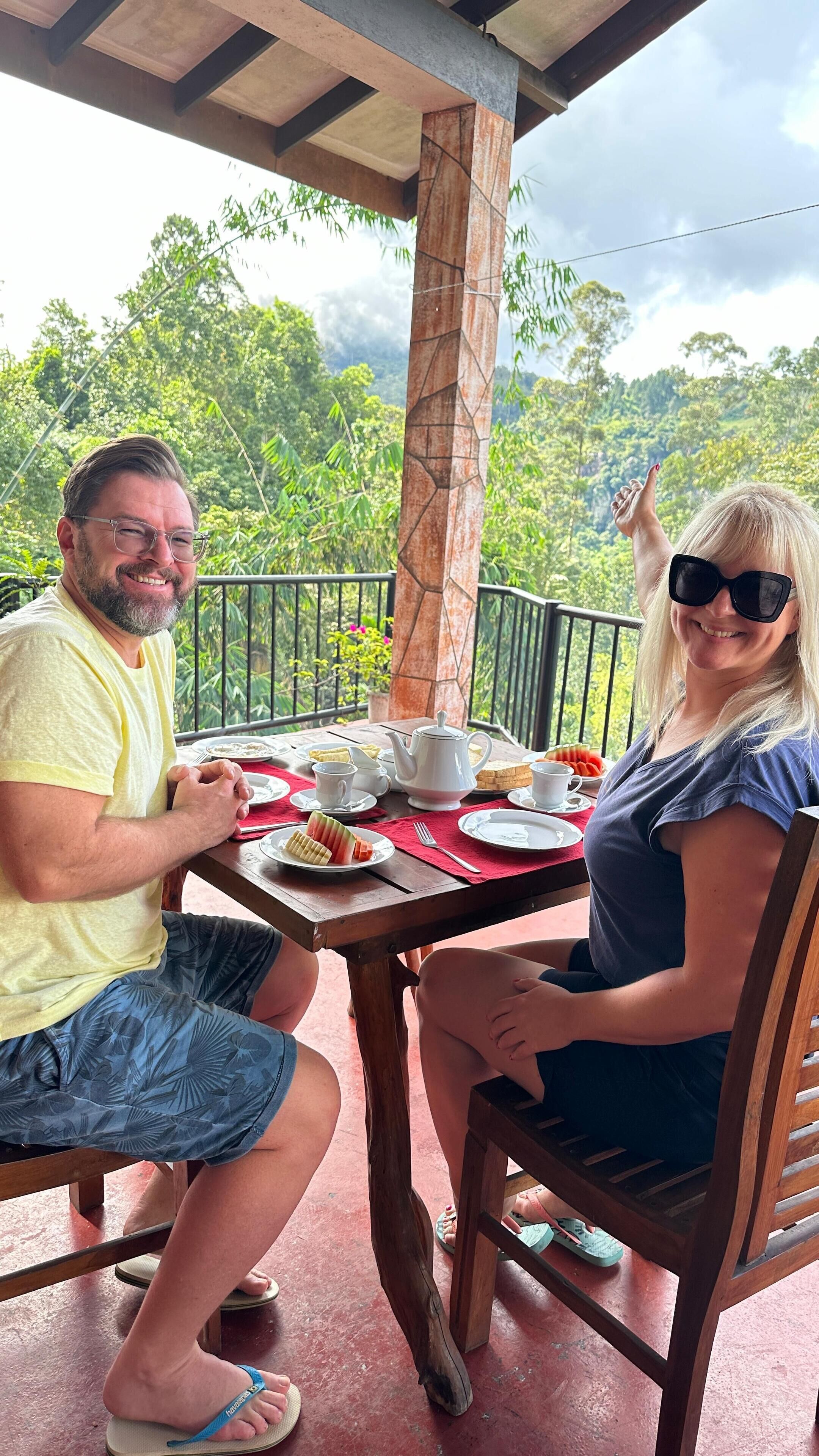 Una pareja cenando en una mesa al aire libre con vistas a abundante vegetación.