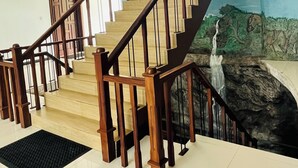 A wooden staircase with a handrail, leading to a landing with a black mat. - HERITAZ VILLA ELLA (Ella)