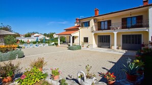 A two-story house with a paved courtyard, a swimming pool, and potted plants.