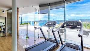 A gym with treadmills and a large window offering a view of the city and mountains. - NEW Beachfront Marítima Condos 2 Pools (Nuevo Nayarit)