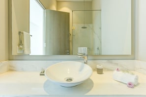 A bathroom with a large mirror, a white sink, and a towel with flowers.