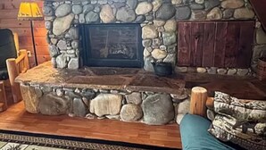 Una chimenea de piedra con diseño rústico, rodeada de leña y un zócalo de piedra.