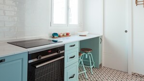 A kitchen with white subway tiles, a stainless steel range hood, a window, and a teal stool. - Central and bright apartment with balconies (M álaga)