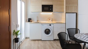 Une cuisine compacte équipée d’un lave-linge, d’un four à micro-ondes et d’une machine à café.