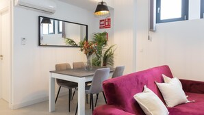 A modern living room with a red sofa, a dining table with chairs, a potted plant, and a pendant light. - Nice apartment in the Central District (Málaga)